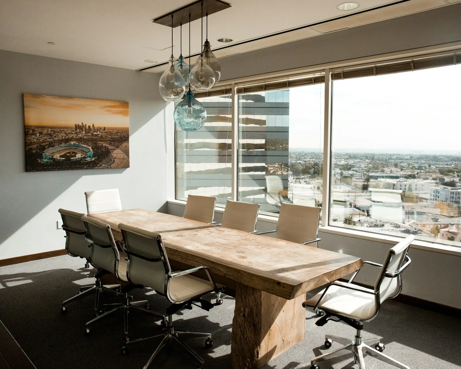Sala de juntas con mesa larga de madera y vista a la ciudad