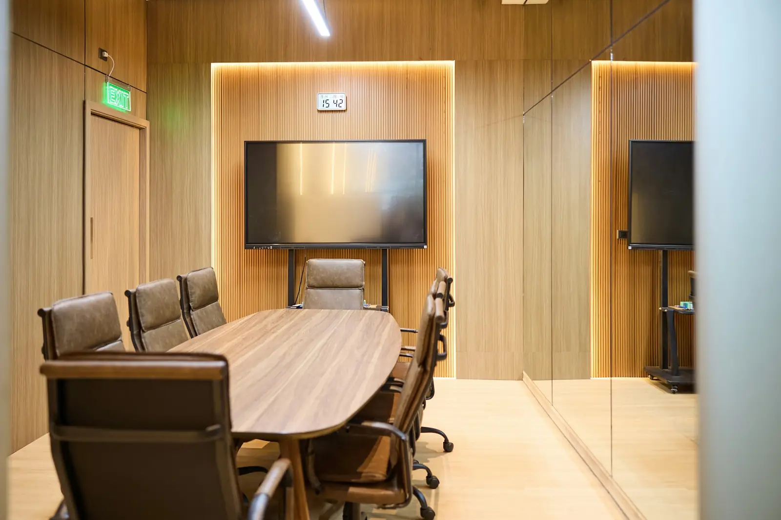 Sala de juntas con mesa ovalada y pantallas en la pared